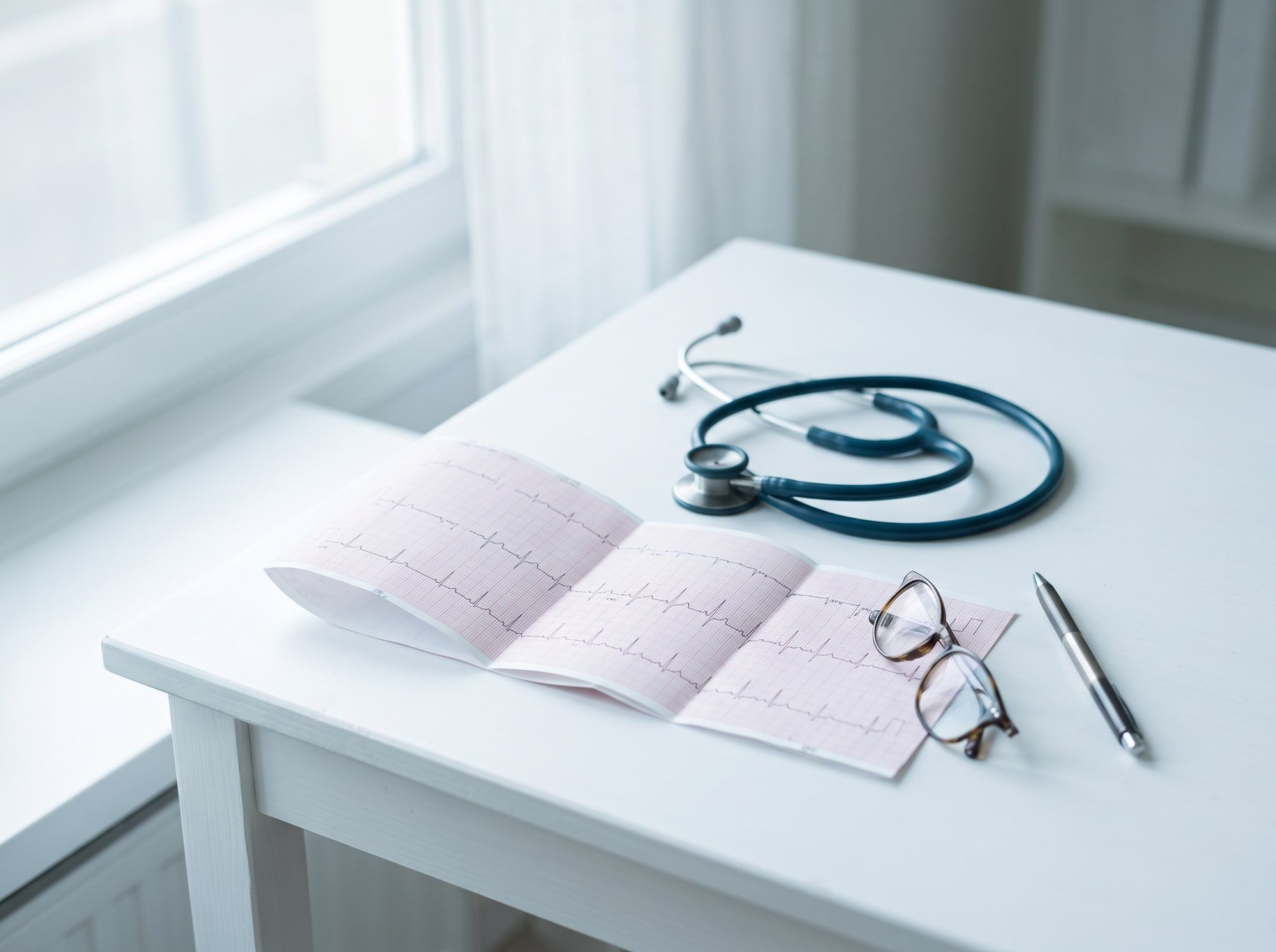 Tracciato di un elettrocardiogramma sulla scrivania, accanto allo stetoscopio